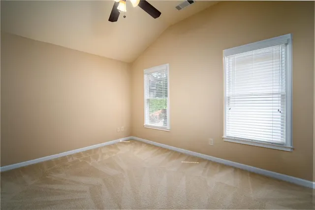 a view of an empty room with window and a ceiling fan