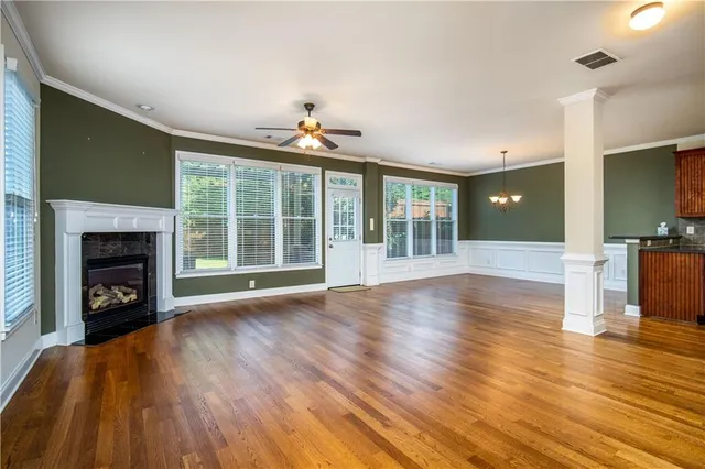 a view of an empty room with wooden floor and a fireplace
