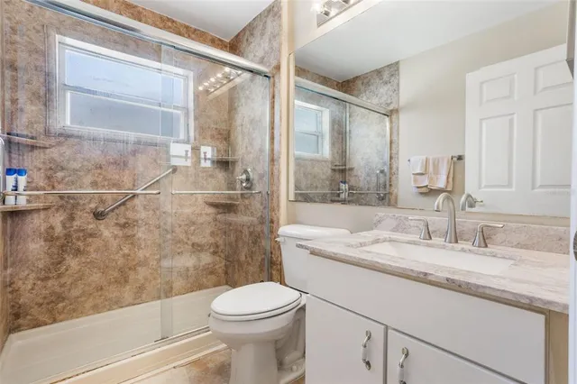 a bathroom with a granite countertop sink toilet and shower