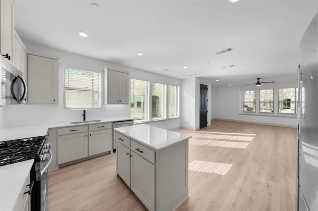 a large white kitchen with stainless steel appliances granite countertop a stove and a sink