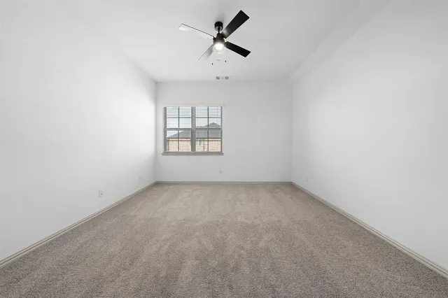 an empty room with a window and ceiling fan