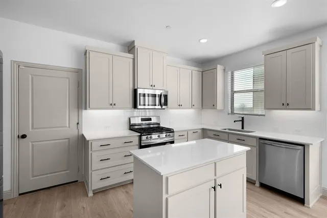 a kitchen with cabinets appliances a sink and a window