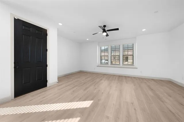 a view of an empty room with a window and wooden floor