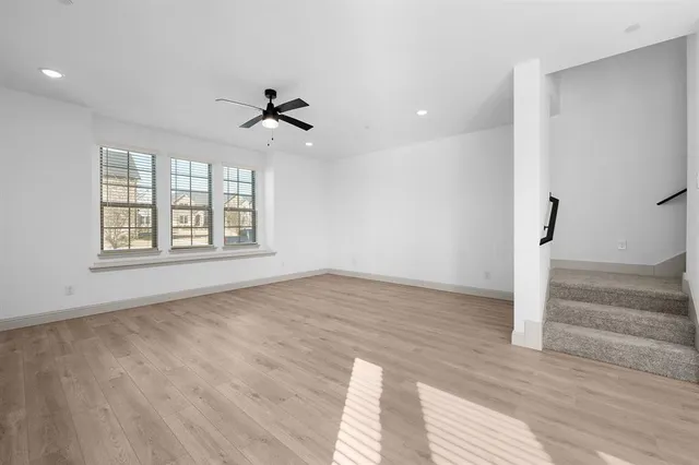 an empty room with wooden floor ceiling fan and windows