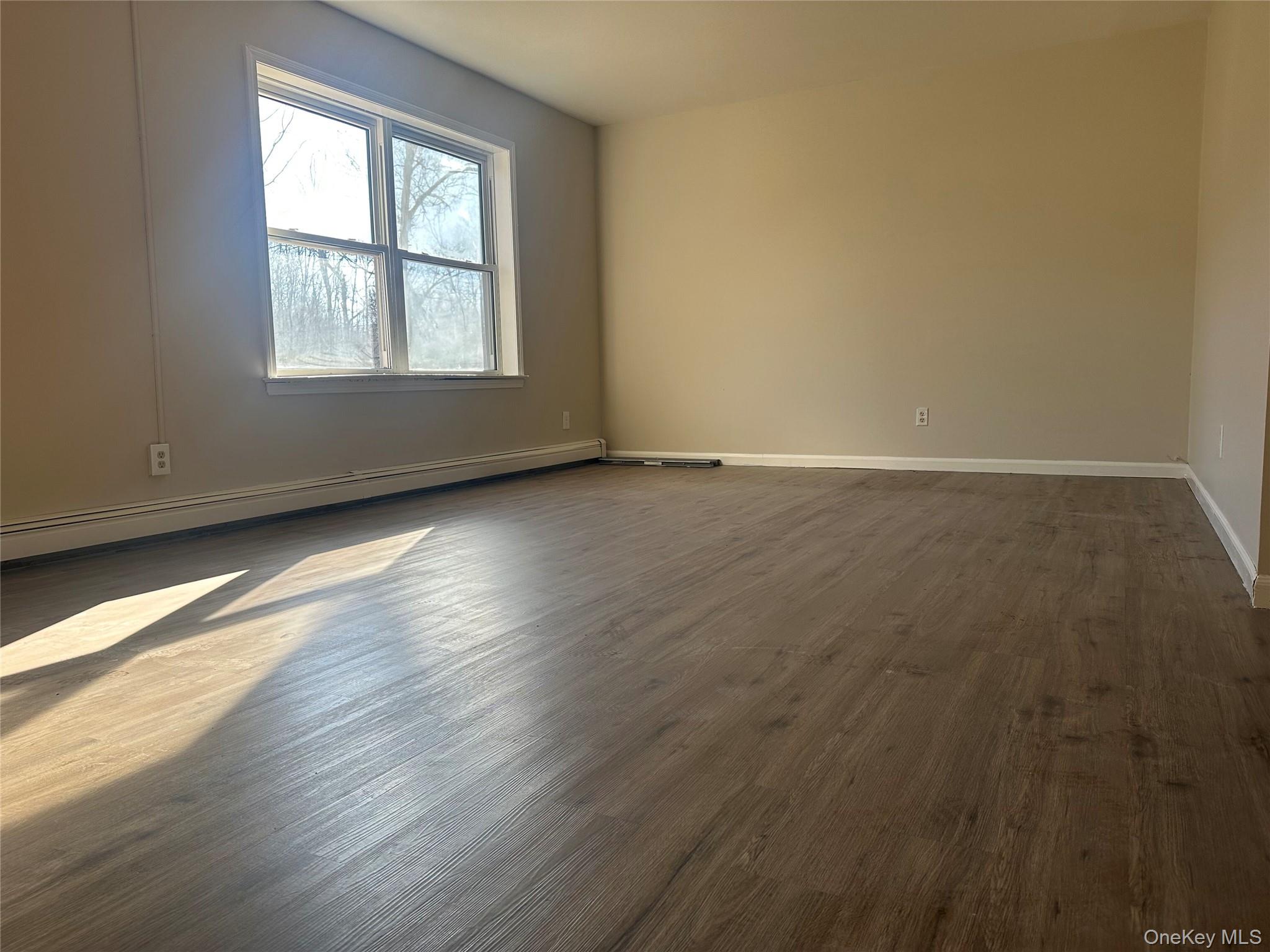 27 Dandelion Lane, Unit A Wallkill, NY 12589 - Photo 4 of 16 an empty room with wooden floor and windows