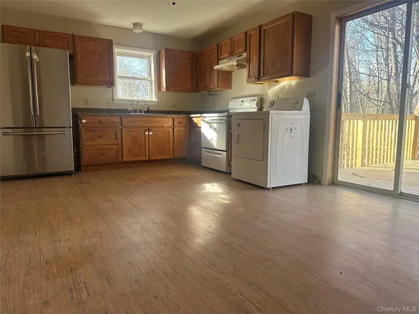 a kitchen with stainless steel appliances granite countertop a refrigerator a oven a sink with wooden cabinets and wooden floor
