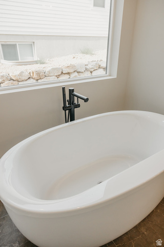 5910 Canyon Rim Road, Unit 619 Lehi, UT 84048 - Photo 36 of 52 Freestanding soaking tub with matte black floor-mounted faucet, large window, and dark-toned floor tiling