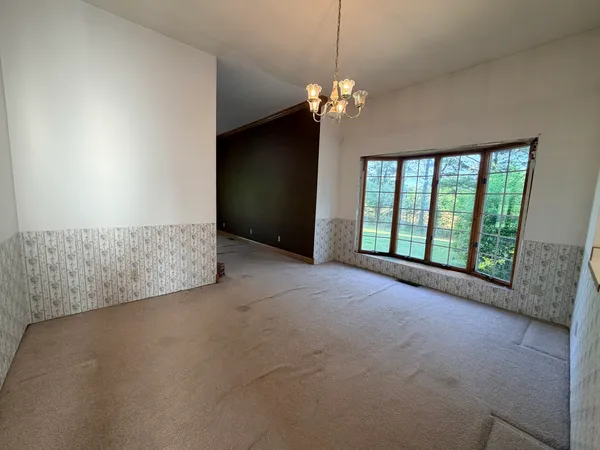 a view of an empty room with chandelier and window