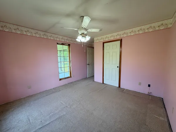 en empty room with windows and ceiling fan