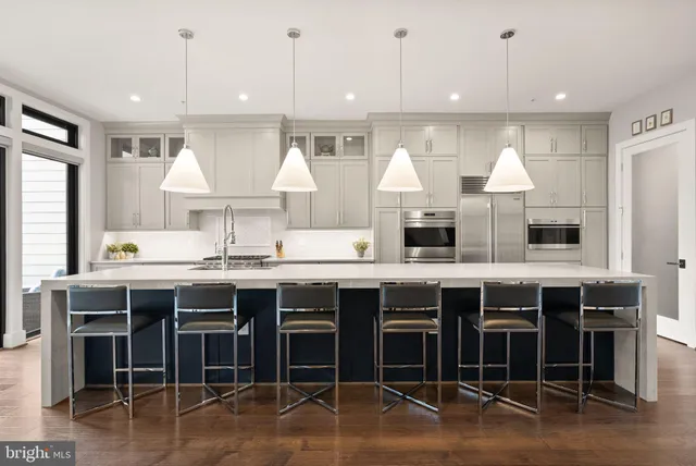 a kitchen with stainless steel appliances kitchen island granite countertop a stove a sink a dining table and chairs with wooden floor