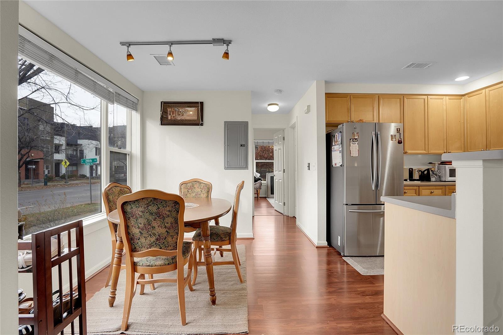 2848 Syracuse Street, Unit 128 Denver, CO 80238 - Photo 6 of 15 a kitchen with stainless steel appliances a refrigerator a stove a dining table and chairs with wooden floor