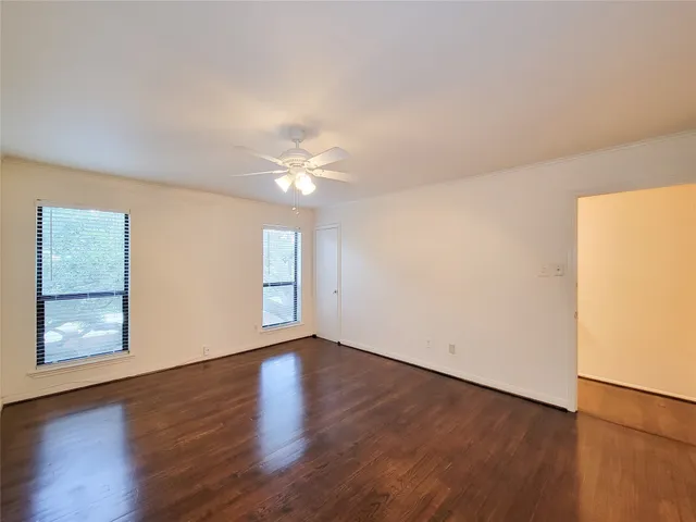 a view of an empty room with a window and wooden floor