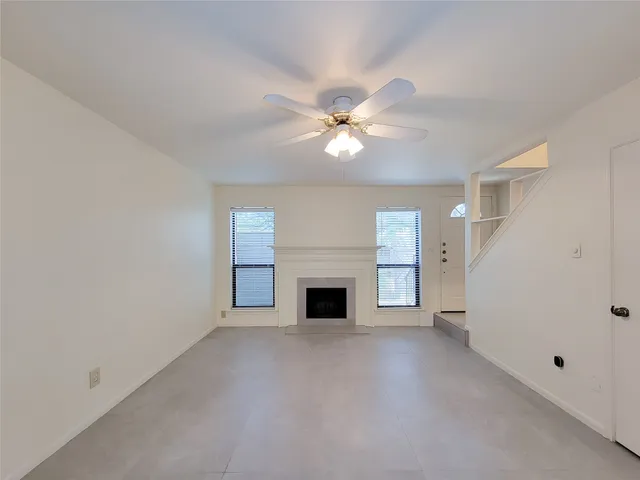 an empty room with windows and fireplace