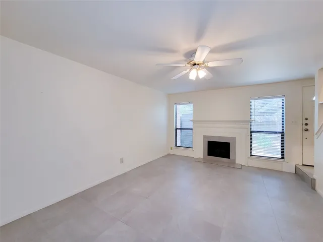 an empty room with a chandelier fan and windows