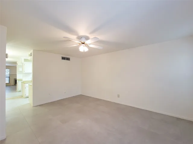 a view of an empty room with a ceiling fan and a window