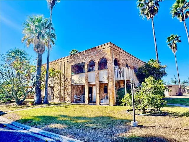a view of a building with a yard and palm trees