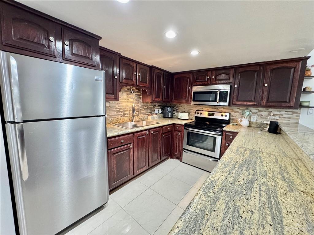2708 Howard Drive, Unit E3 McAllen, TX 78503 - Photo 11 of 30 a kitchen with stainless steel appliances granite countertop a refrigerator a stove a sink and a microwave