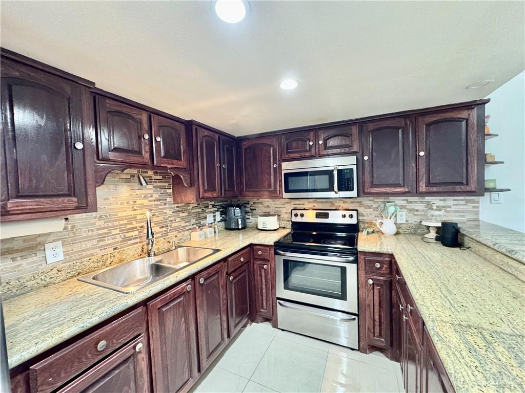 2708 Howard Drive, Unit E3 McAllen, TX 78503 - Photo 12 of 30 a kitchen with wooden cabinets and stainless steel appliances