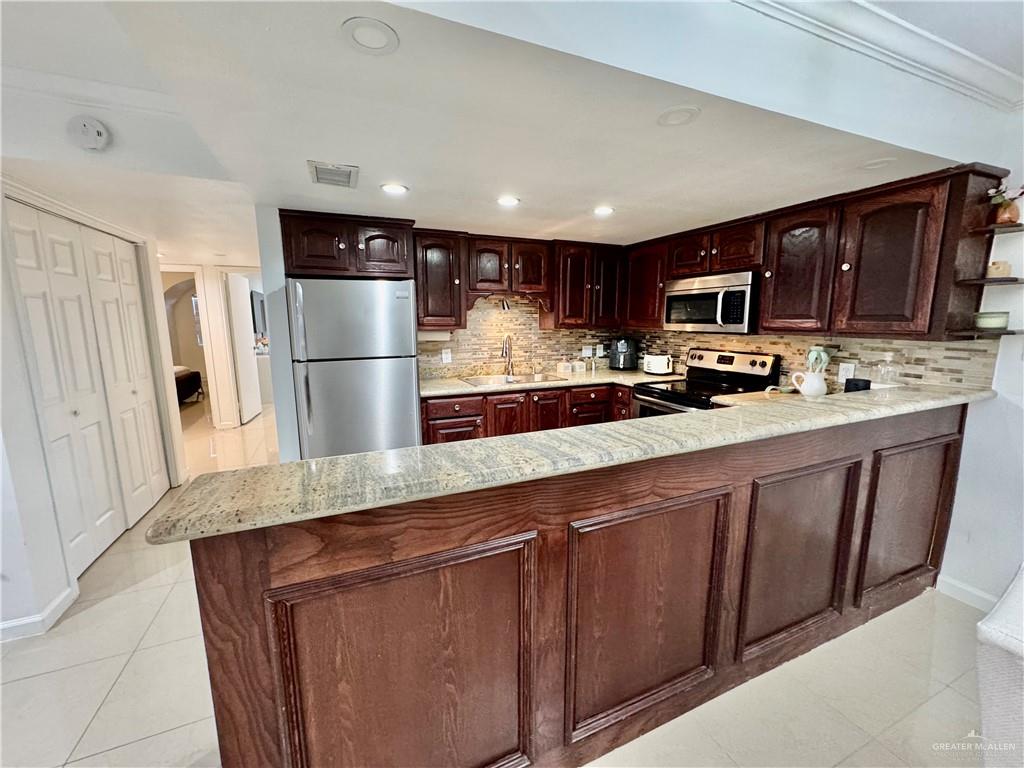 2708 Howard Drive, Unit E3 McAllen, TX 78503 - Photo 13 of 30 a kitchen with stainless steel appliances granite countertop a refrigerator a sink a stove a microwave a counter space and cabinets