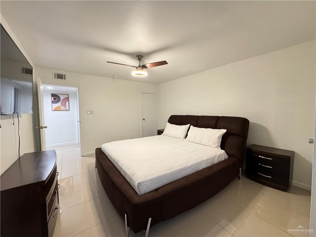 2708 Howard Drive, Unit E3 McAllen, TX 78503 - Photo 23 of 30 a spacious bedroom with a bed and a chandelier