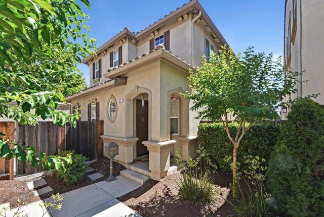 a view of a white house with a small yard and plants