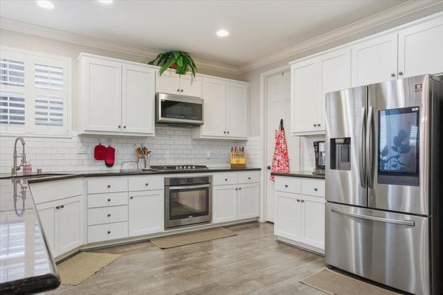 a kitchen with granite countertop stainless steel appliances a sink cabinets and a window