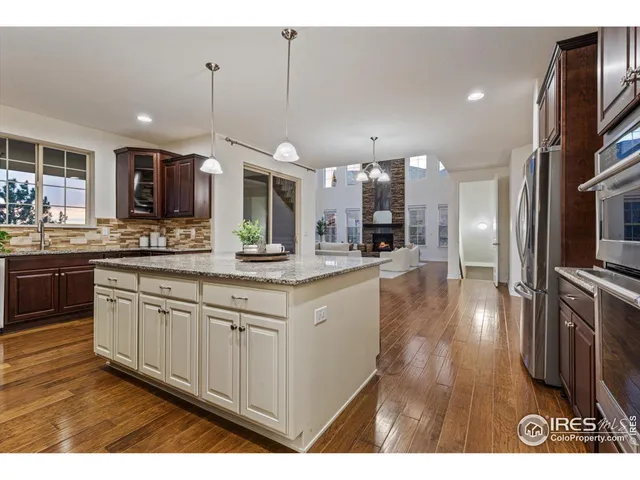a kitchen with stainless steel appliances granite countertop a sink a stove and a wooden floors