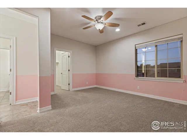 an empty room with windows and ceiling fan