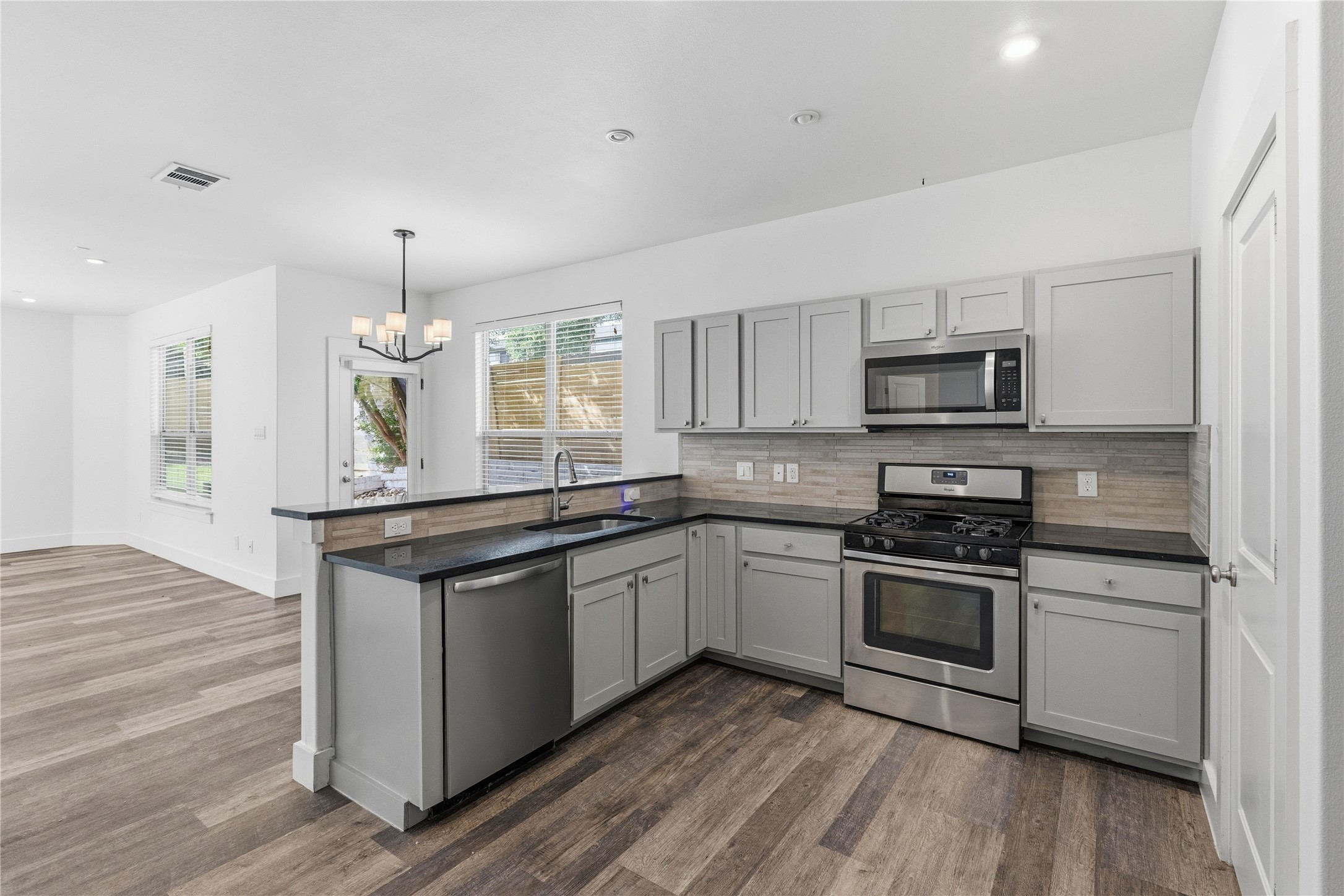 4124 Valley View Road, Unit 4A & 4B Austin, TX 78704 - Photo 26 of 40 A contemporary kitchen features gray cabinetry, stainless steel appliances, and sleek countertops, with an open layout extending into the living area.