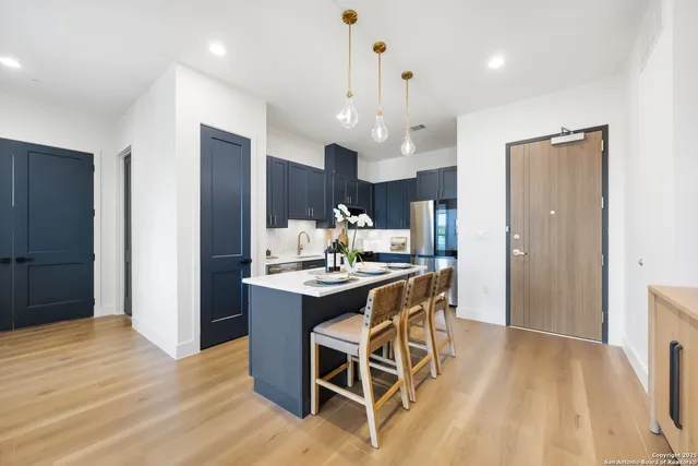 a kitchen with stainless steel appliances a dining table chairs and wooden floor