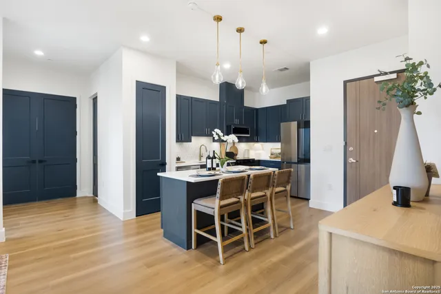 a kitchen with stainless steel appliances kitchen island granite countertop dining table chairs and a large window