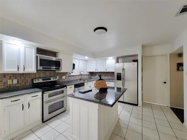 a kitchen with white cabinets and appliances
