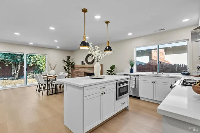 a kitchen with a stove a sink a kitchen island a dining table and chairs with wooden floor