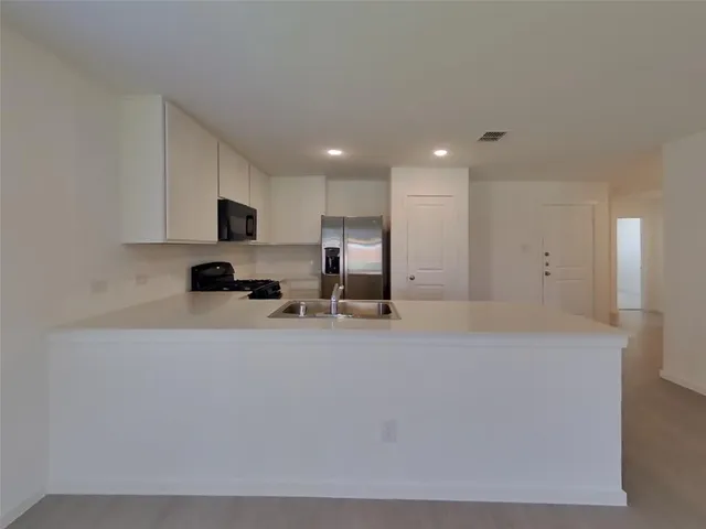 a large white kitchen with kitchen island granite countertop a sink a stove and a refrigerator