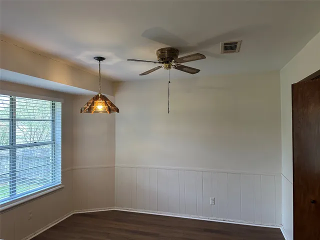 an empty room with wooden floor fan and windows