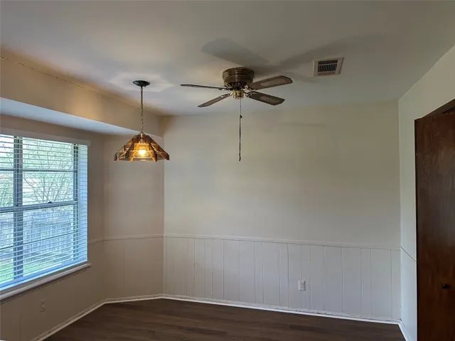 an empty room with wooden floor fan and windows