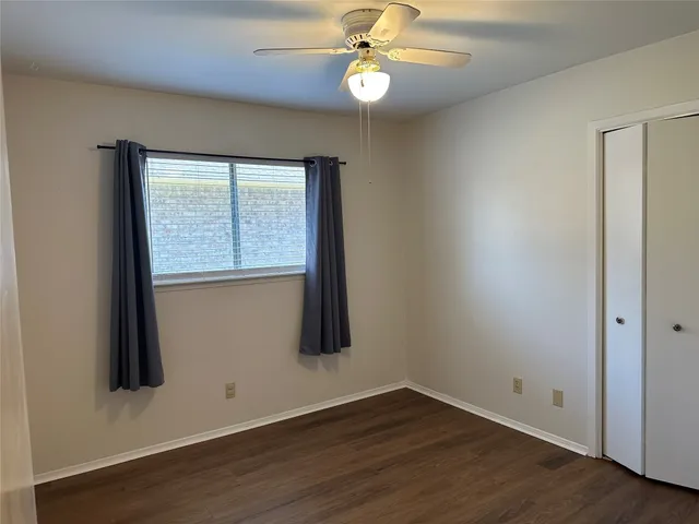 an empty room with wooden floor closet and windows