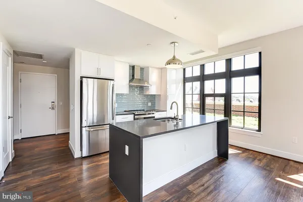 a kitchen with stainless steel appliances granite countertop a refrigerator a sink and wooden floors