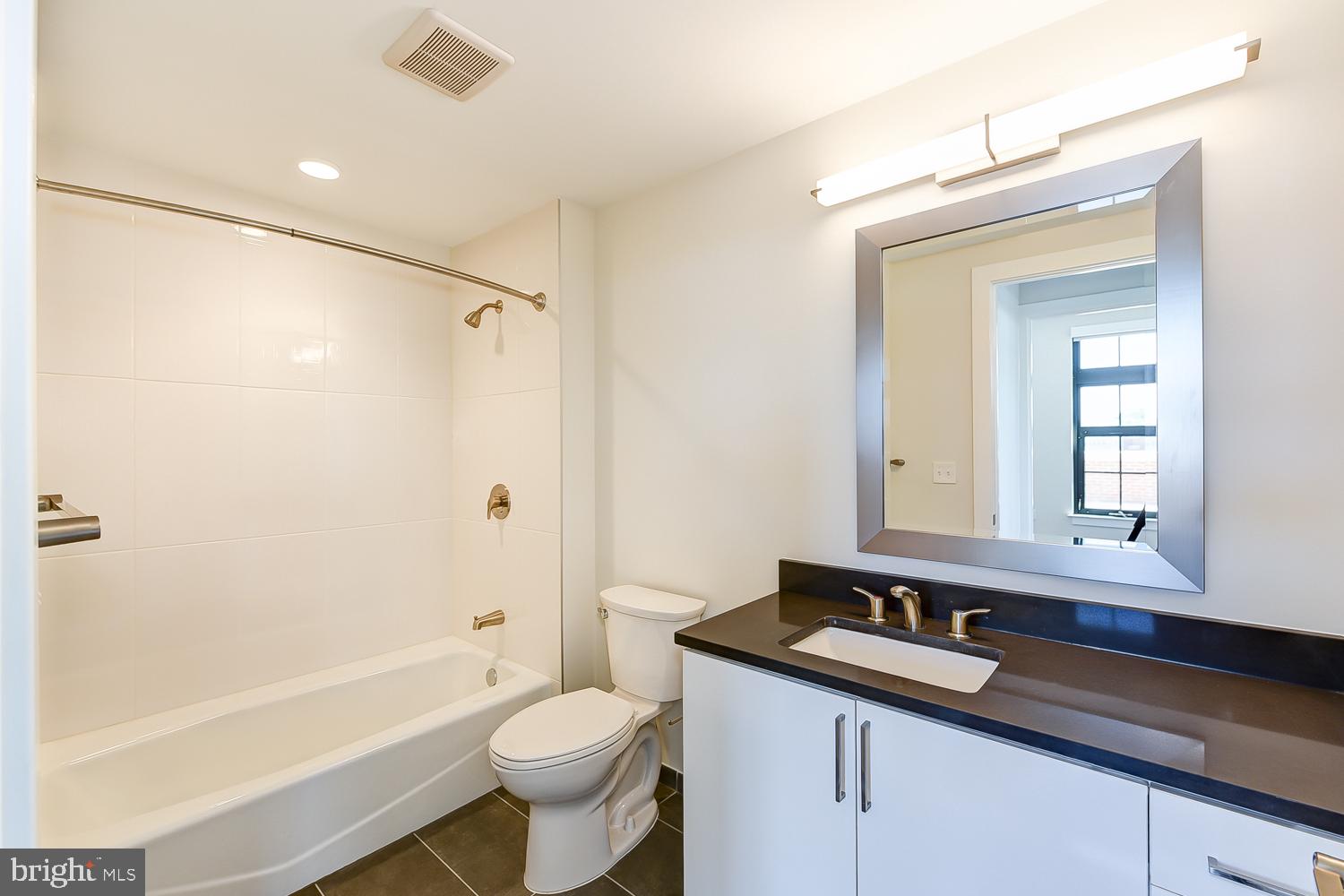 901 H Street Northeast, Unit 643 Washington, DC 20002 - Photo 14 of 82 a bathroom with a granite countertop sink mirror toilet and bathtub