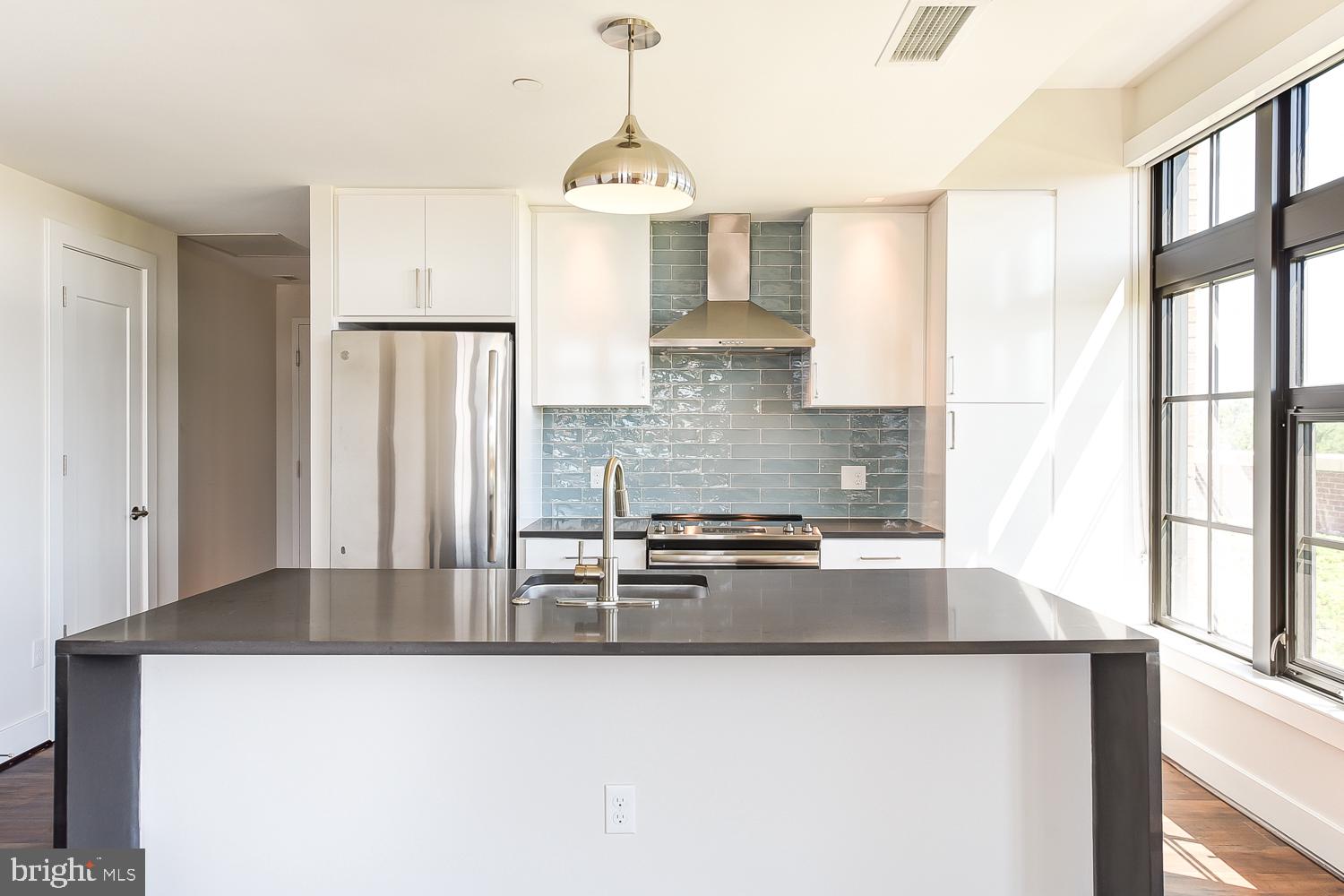 901 H Street Northeast, Unit 643 Washington, DC 20002 - Photo 3 of 82 a kitchen with stainless steel appliances granite countertop a refrigerator a sink dishwasher a stove and white countertops with wooden floor