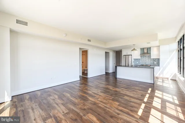 a view of an empty room with wooden floor and a window