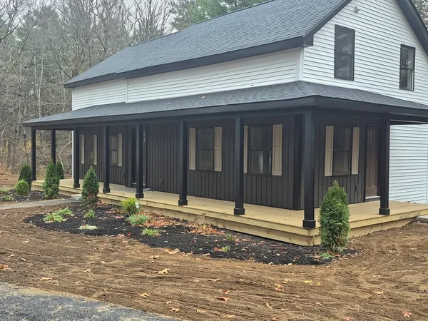 a view of a house with small yard plants and wooden fence