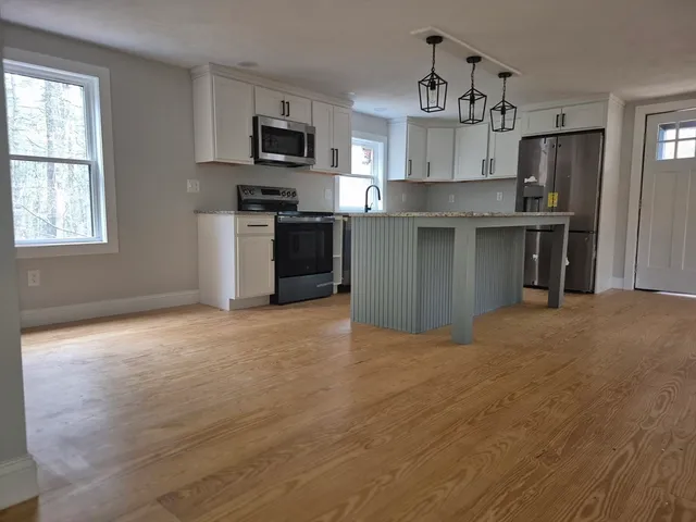 a kitchen with stainless steel appliances granite countertop a stove top oven a refrigerator and a sink