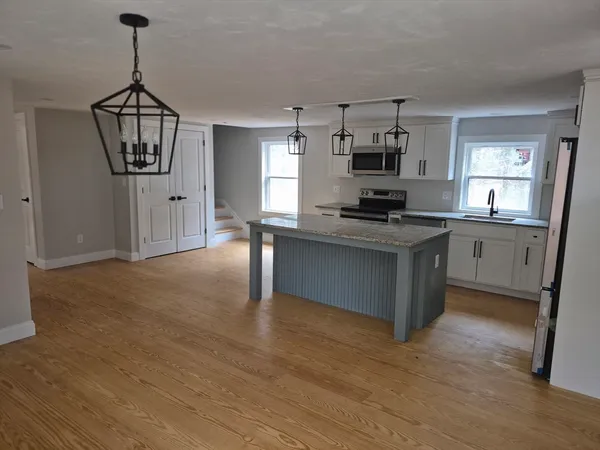 a kitchen with stainless steel appliances granite countertop a stove cabinets and wooden floor