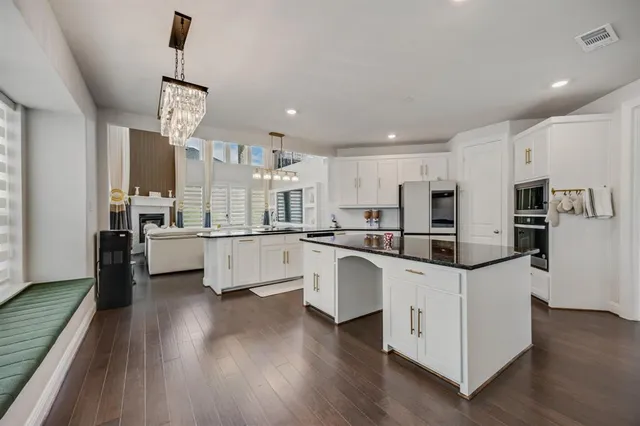 a kitchen with stainless steel appliances granite countertop a white cabinets and a clock on the wall