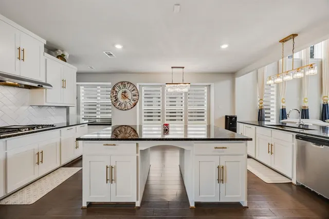 a kitchen with stainless steel appliances granite countertop a stove and white cabinets
