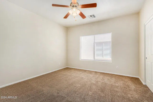 an empty room with a window and a fan