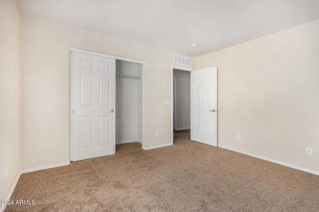 an empty room with a chandelier fan and windows