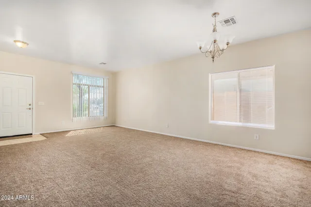 an empty room with windows and chandelier fan