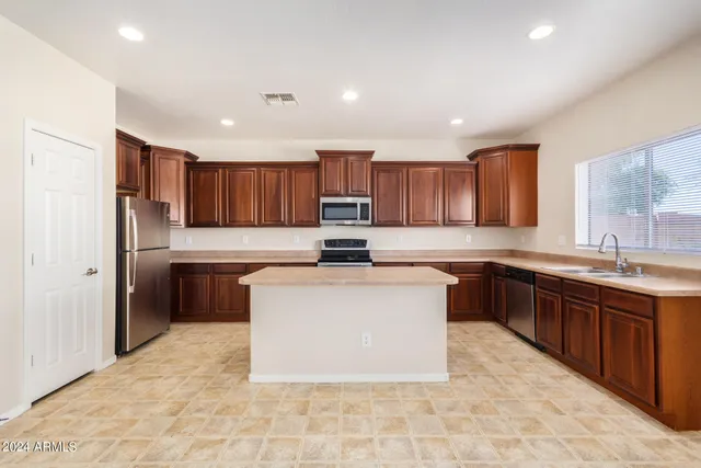 a kitchen with stainless steel appliances granite countertop a table chairs sink and cabinets